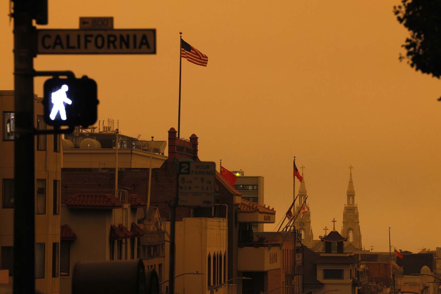 epa08657791 A pedestrian light illuminates a crosswalk on California Street over an orange overcast sky in the afternoon in San Francisco, California, USA, 09 September 2020. California wildfire smoke ...