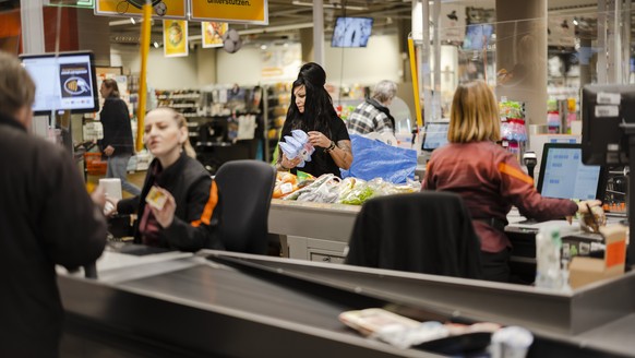 Salespeople Stefania Kaufmann, right, and Arbenita Dalipi, left, serve Tammy Gross, center, at Migros at Limmatplatz, on Thursday, February 17, 2022, in Zurich.  (KEYSTONE/Michael Buho...