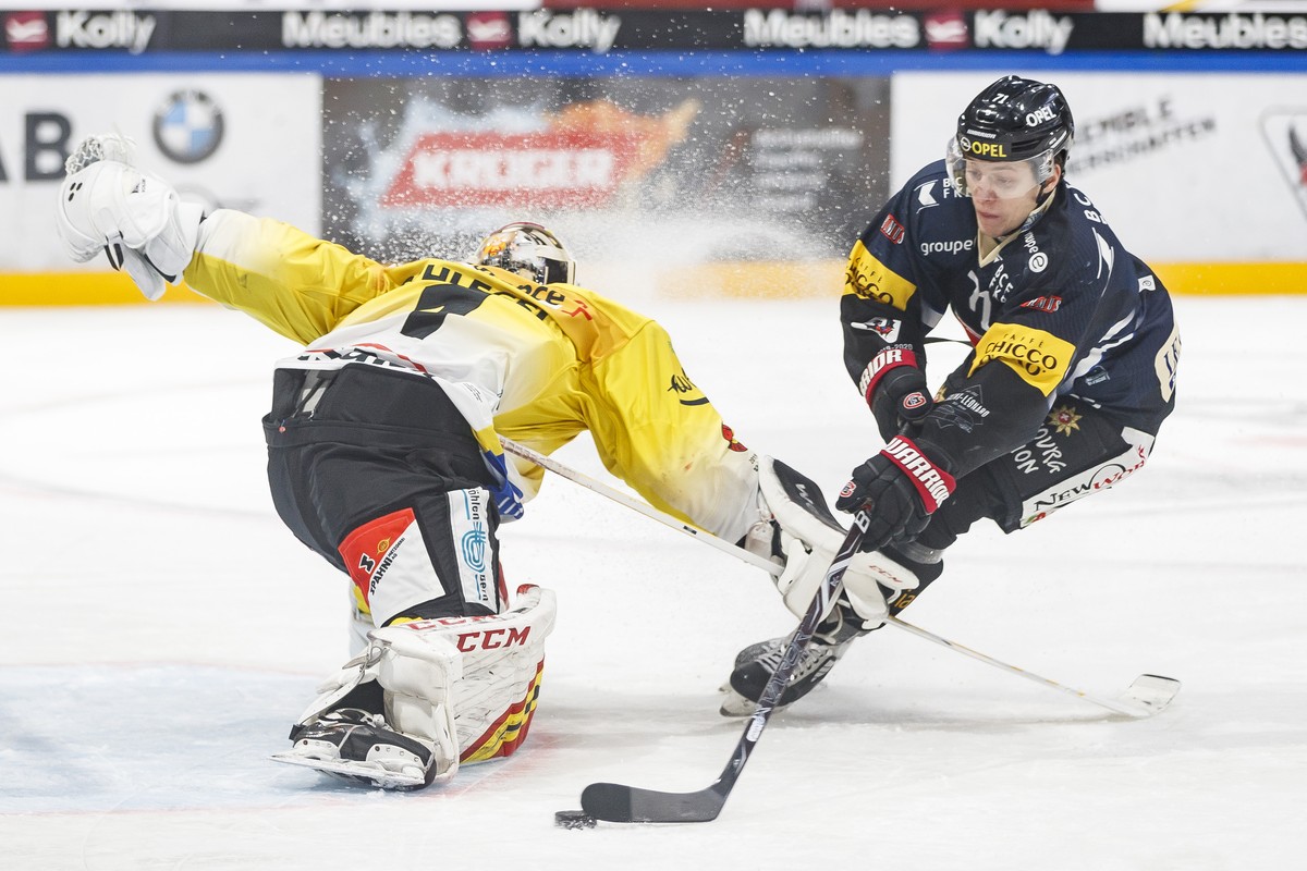 L'attaquant fribourgeois Killian Mottet, droite, lutte pour le puck avec le gardien bernois Niklas Schlegel, gauche, lors de la rencontre du championnat suisse de hockey sur glace de National Lea ...