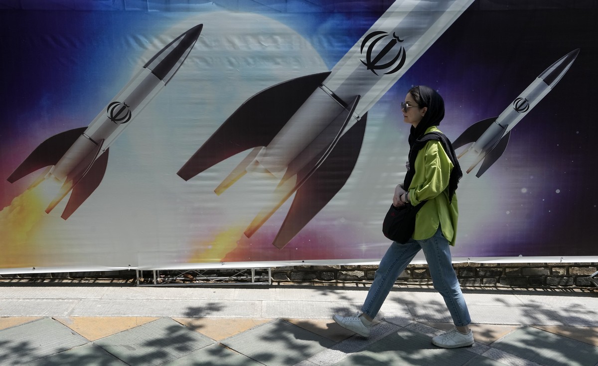 Une femme passe devant une bannière montrant des missiles en cours de lancement, dans le nord de Téhéran.