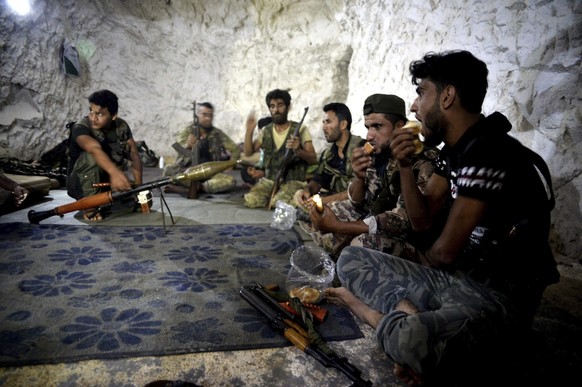 In this Sunday, Sept. 9, 2018 photo, fighters with the Free Syrian army eat in a cave where they live, in the outskirts of the northern town of Jisr al-Shughur, Syria, west of the city of Idlib. In th ...