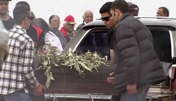 In this image made from video, the oldest human remains in a coffin are unloaded from a hearse for a traditional ceremony in Lake Mungo, Australia, Friday, Nov. 17, 2017. The human remains found in Au ...