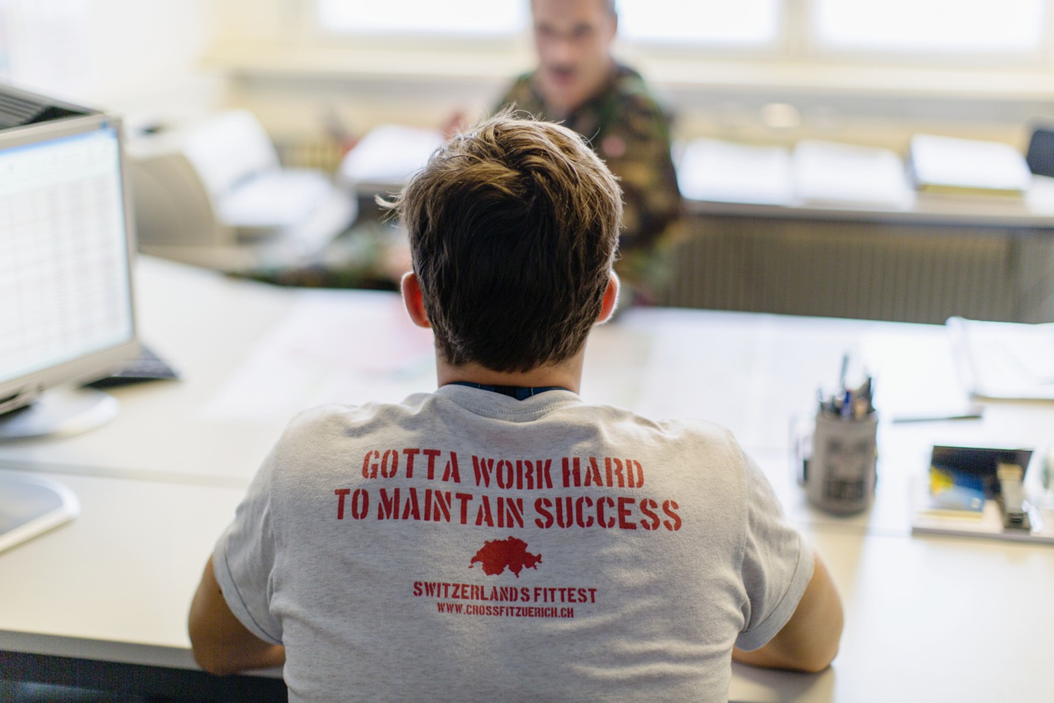 A young man sits in the office of colonel Rene Chastonay, who will decide on the military function of the future recruit, pictured on August 5, 2013, in a recruitment center of the Swiss Armed Forces  ...