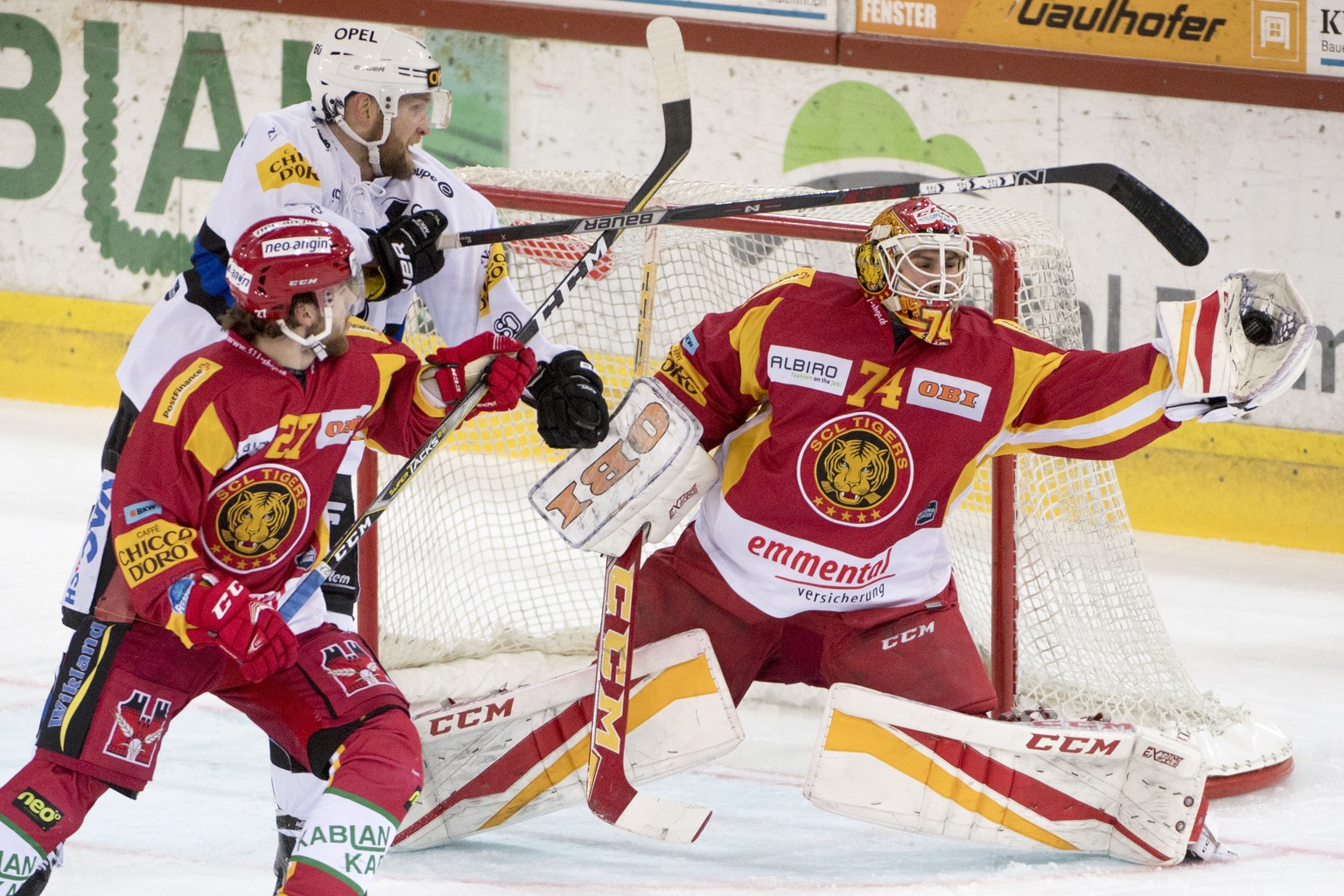 Tigers Goalie Ivars Punnenovs und Anthony Huguenin, links, kaempfen um den Puck, gegen Fribourgs Kevin Kuehni, Mitte, waehrend dem Meisterschaftsspiel der National League, zwischen den SCL Tigers und  ...