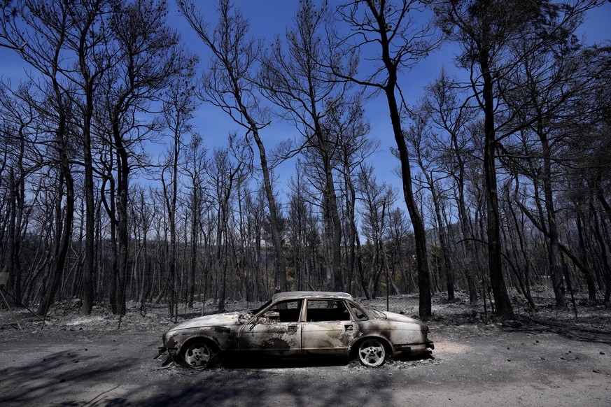 A burn car is seen at a road during a wildfire at Ipokratios Politia, in northern Athens, Greece, Saturday, Aug. 7, 2021. Wildfires rampaged through massive swathes of Greece&#039;s last remaining for ...