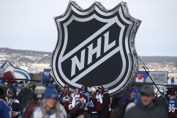 FILE - In this Feb. 15, 2020, file photo, fans pose below the NHL league logo at a display outside Falcon Stadium before an NHL Stadium Series outdoor hockey game between the Los Angeles Kings and Col ...