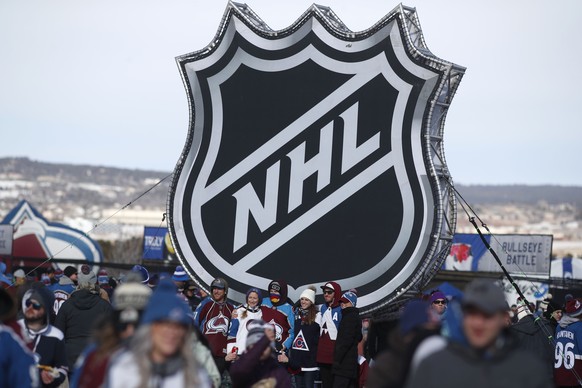 FILE - In this Feb. 15, 2020, file photo, fans pose below the NHL league logo at a display outside Falcon Stadium before an NHL Stadium Series outdoor hockey game between the Los Angeles Kings and Col ...