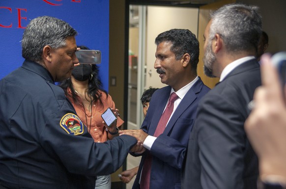 Muhammad Imtiaz Hussain, center, thanks Albuquerque Police Chief Harold Medina, left, following a news conference, Tuesday, Aug. 9, 2022, to announce the arrest of Muhammad Syed, a suspect in the rece ...