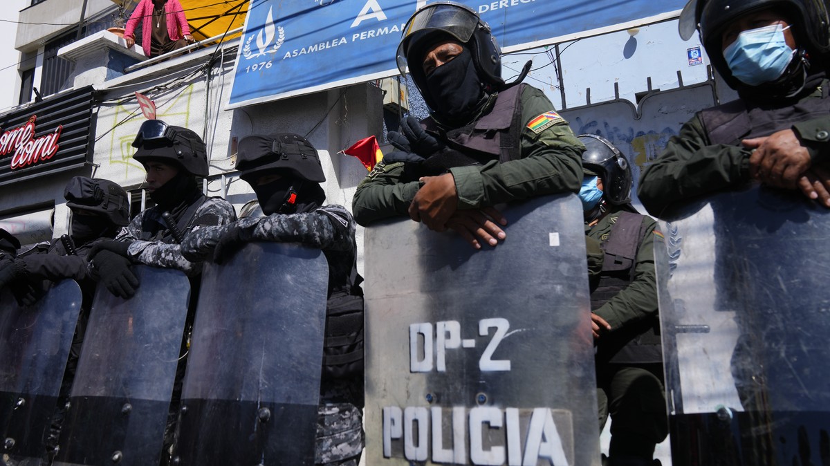 Police stand guard at the the Permanent Assembly of Human Rights of Bolivia (APDHB) office, as Amparo Carvajal, top left, speaks to supporters down below in La Paz, Bolivia, Monday, July 17, 2023. Car ...
