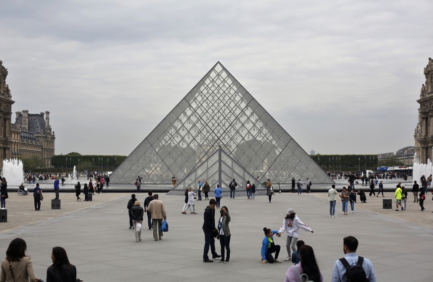 Tourists walk around the pyramide of the Louvre museum, in Paris, Friday, May 17, 2019. Paris&#039; Louvre museum is paying tribute to the architect of its giant glass pyramid, I.M. Pei, who has died  ...