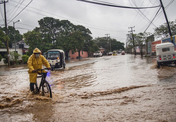 epa09987115 People transit through a flooded avenue in the municipality of Tehuantepec, Oaxaca state, Mexico, 30 May 2022. Hurricane Agatha, a category 2 storm formed in the Pacific, made landfall in  ...