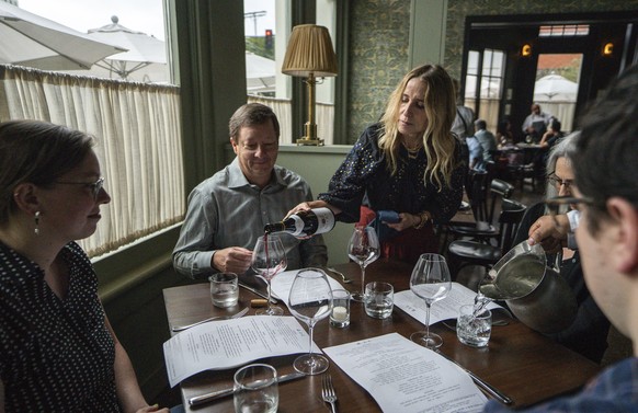 In this Saturday, June 19, 2021, photo, Caroline Styne, owner and wine director at The Lucques Group, serves wine to attorney Alec Nedelman, celebrating early &quot;Father&#039;s Day &quot;with his fa ...