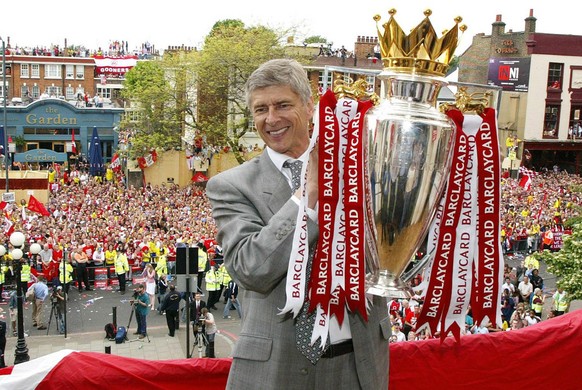 Arsenal manager Arsene Wenger holds up the English Premiership Trophy to thousands of jubilant fans outside Islington Town Hall in North London, Sunday May 16, 2004, during their victory parade. (AP P ...