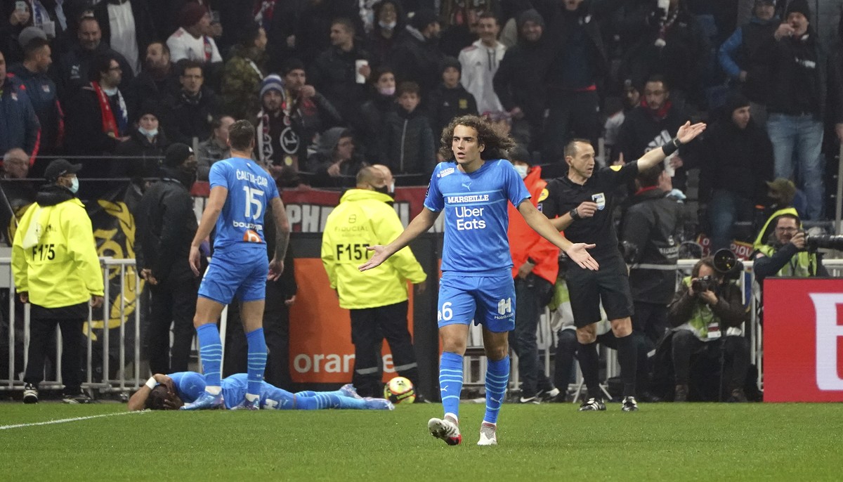 Marseille's Matteo Guendouzi gestures as his teammate Dimitri Payet lays on the field after being injured by an object thrown by a Lyon's supporter during the French League One soccer match  ...