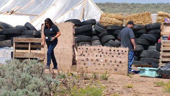 Taos County Planning Department officials Rachel Romero, left, and Eric Montoya survey property conditions at a disheveled living compound at Amalia, N.M., on Tuesday, Aug. 7, 2018. A New Mexico sheri ...