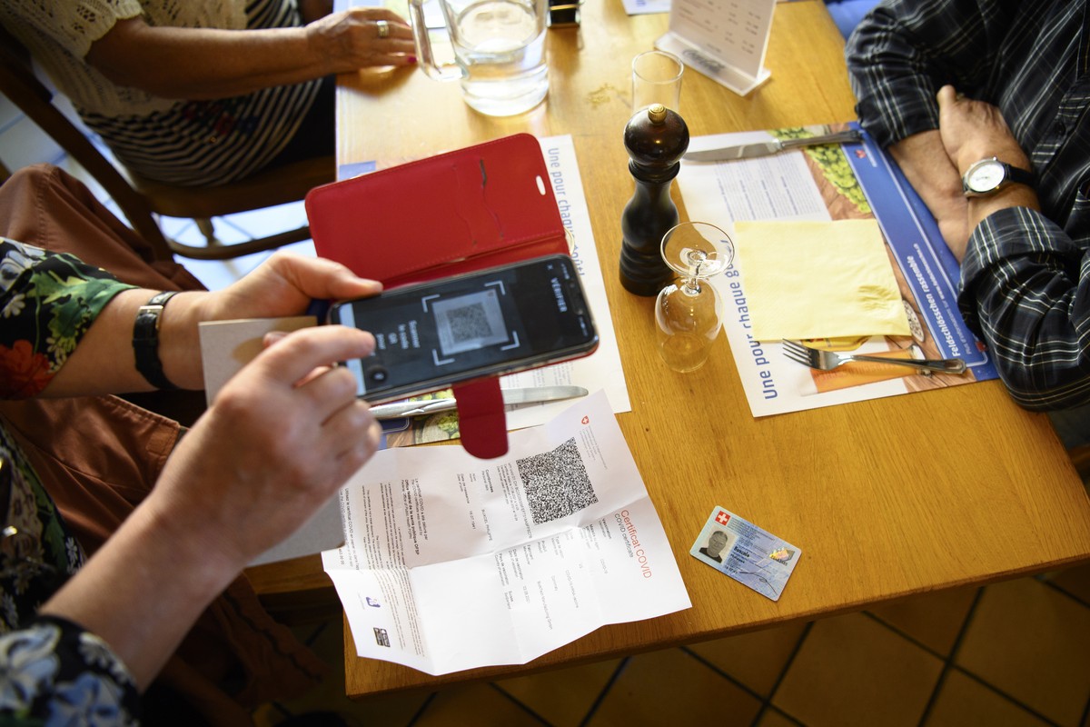 Une serveuse verifie un certificat COVID en papier d'un client a l'aide d'un smartphone et l'application Certificat Covid Check dans le cafe restaurant de L'Europe ce lundi 13 ...