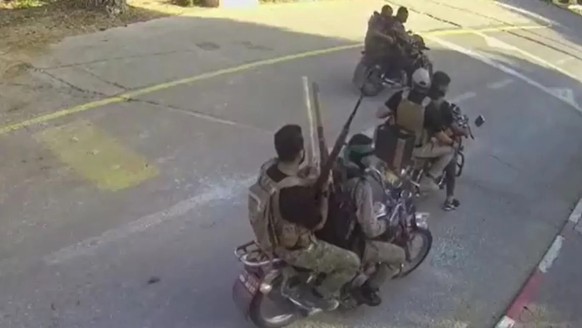 Armed Hamas terrorists ride motorcycles through a kibbutz near the Gaza Strip.