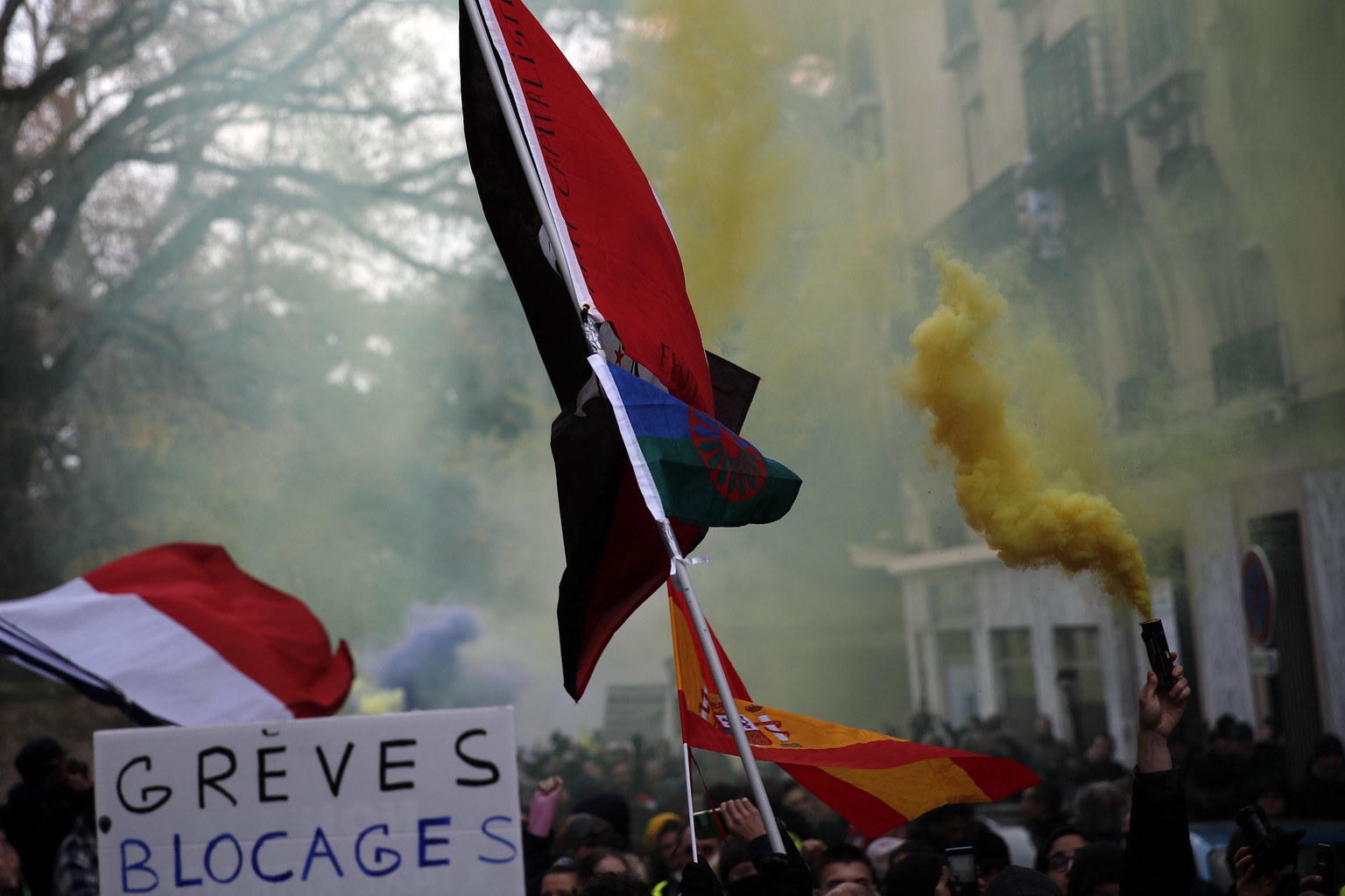 A sign reading &quot;Strikes Blockades&quot;, flags with flares are displayed during the yellow vests 56th round demonstration in Paris, Saturday, Dec. 7, 2019. A few thousand yellow vest protesters m ...