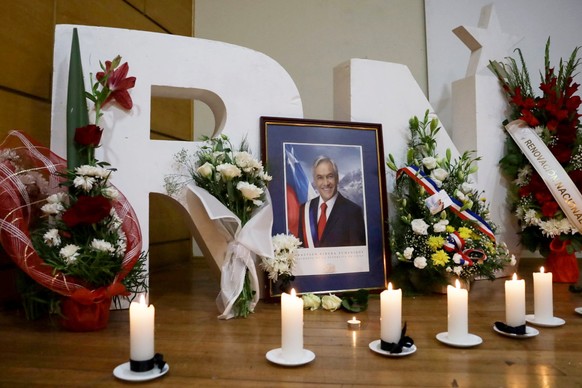 epa11132831 Flowers and candles are placed next to a portrait of former President Sebastian Pinera during a gathering of supporters at Renovacion Nacional party&#039;s headquarters to honor his memory ...