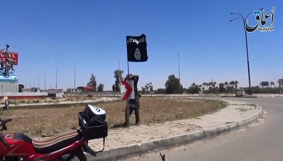 Ein IS-Mitglied markiert mit einer Fahne, dass Ramadi erobert ist.