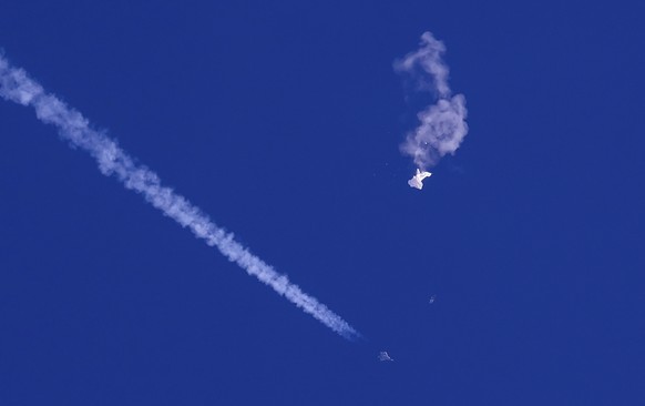 In this photo by Chad Fish, the remains of a large balloon float above the Atlantic Ocean, just off the coast of South Carolina, with a fighter jet and its contrail below, Feb. 4, 20...
