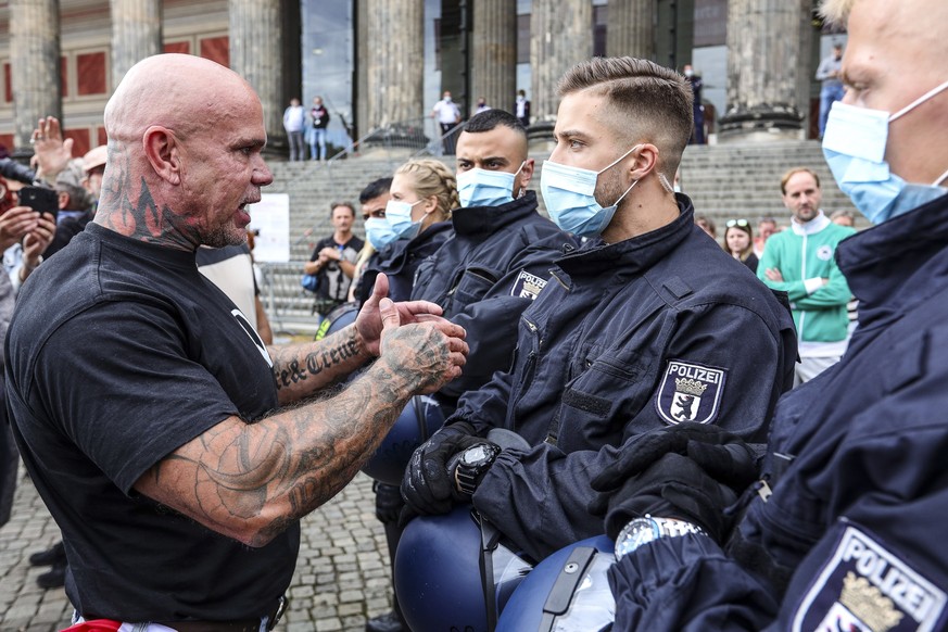 epa08540601 A protester talks to German police officers during an anti-restrictions protest lead by German vegan chef Attila Hildmann, at the Lustgarten park in Berlin, Germany, 11 July 2020. Hildmann ...