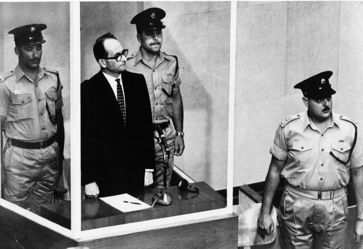 FILE - The 1961 file photo shows Adolf Eichmann standing in his glass cage, flanked by guards, in the Jerusalem courtroom during his trial in 1961 for war crimes committed during World War II. The ori ...
