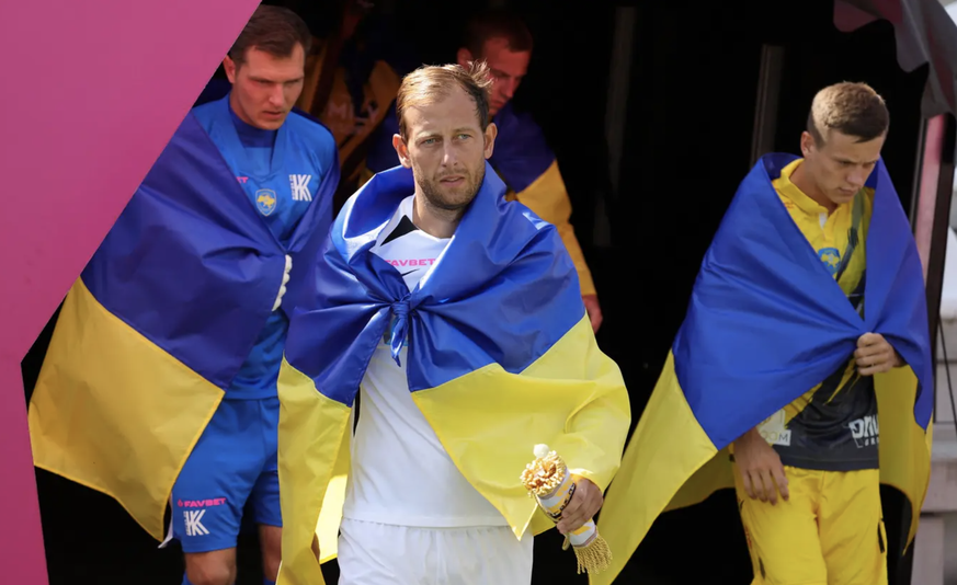 Vadym Mitko, Captain des FC Kolos, in die ukrainische Flagge gehüllt.