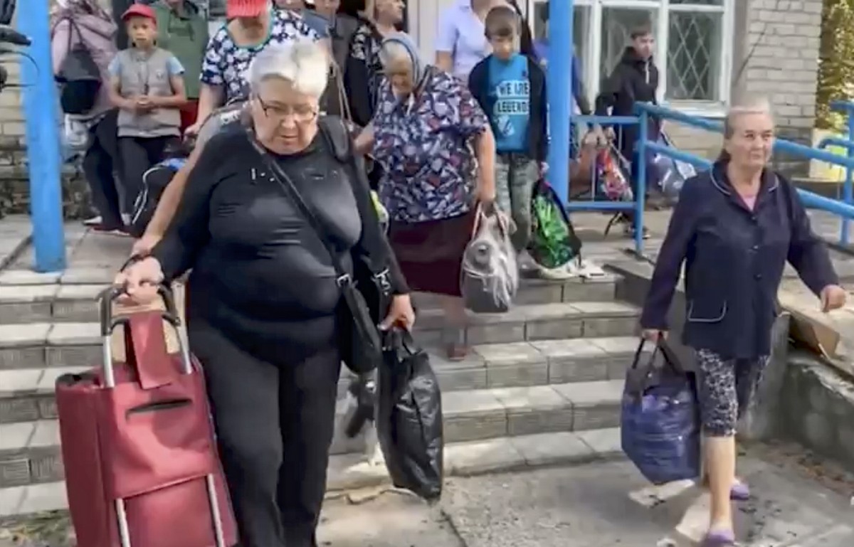 epa11547786 A handout photo made available by the Russian Emergency Ministry's press service shows people preparing to enter buses as they are evacuated from their homes in the border settlements ...