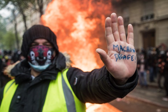 epa09172251 A 'Gilet Jaune' (Yellow Vest) protester shows a message on his hand reading 'Macron Degage' (Macron Clears) during the annual May Day march in Paris, France, 01 May 2021. Labour Day, also  ...