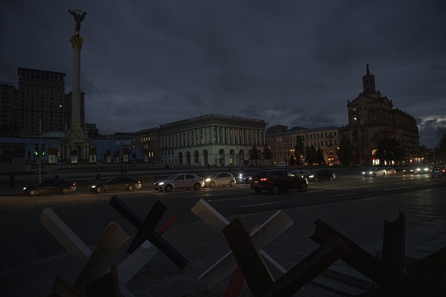 Cars pass in Independence Square at twilight in Kyiv, Ukraine, Monday, Oct. 31, 2022. Rolling blackouts are increasing across Ukraine as the government rushes to stabilise the energy grid and repair t ...