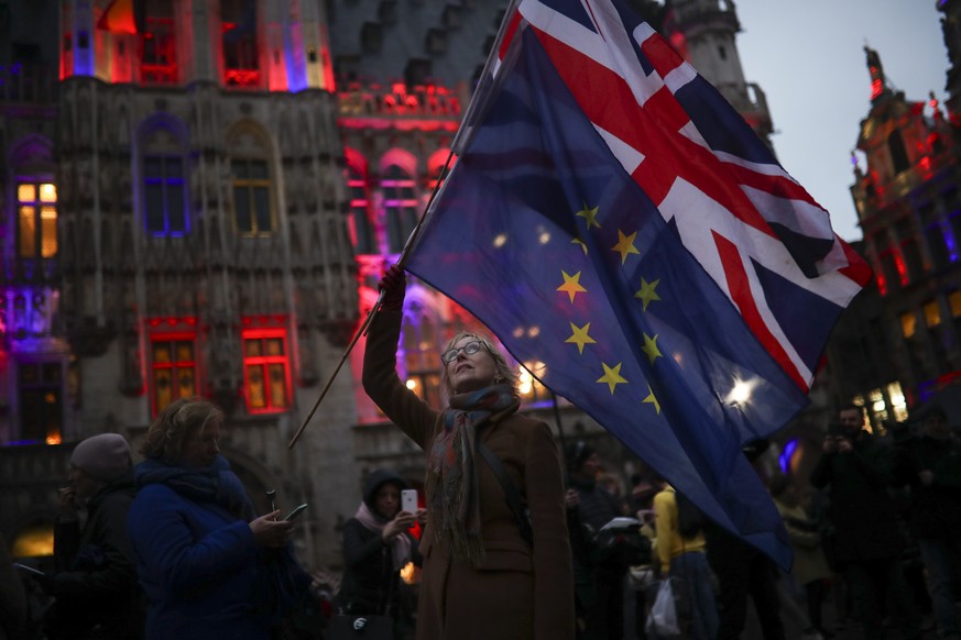 A woman holds up the Union and the European Union flags during an event called &quot;Brussels calling&quot; to celebrate the friendship between Belgium and Britain at the Grand Place in Brussels, Thur ...