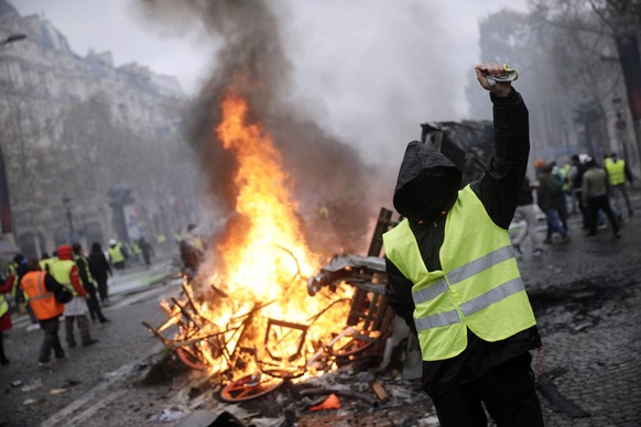 Demonstrators, called the yellow jackets, protest over the cost of fuel taxes on the famed Champs-Elysees avenue, in Paris, France, Saturday, Nov. 24, 2018. French police fired tear gas and water cann ...