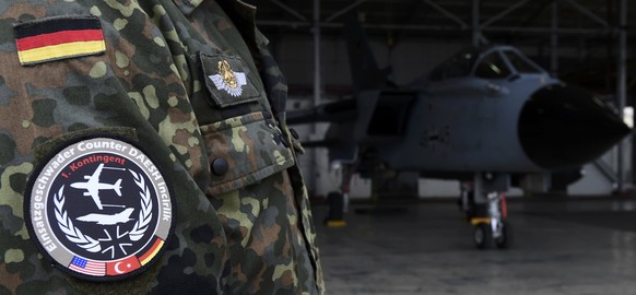 A soldier of the German Armed Forces Bundeswehr wears a patch of the combat wing (Einsatzgeschwader) Counter DAESH Incirlik next to a German Tornado jet in a hangar before a statement of the German an ...