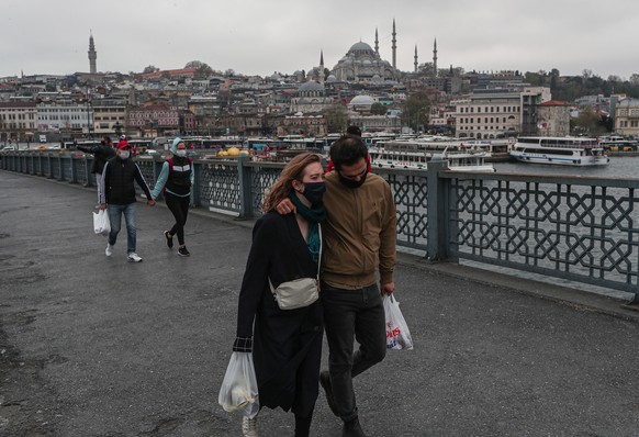 epa08373497 People wearing face masks as they walk on the Galata Bridge in Istanbul, Turkey, 20 April 2020. Turkey suspended all international flights and all inter-city travels are subject to local a ...
