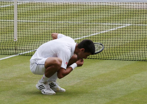 Novak Djokovic of Serbia eats some grass off Centre Court after winning his Men&#039;s Singles Final match against Roger Federer of Switzerland at the Wimbledon Tennis Championships in London, July 12 ...