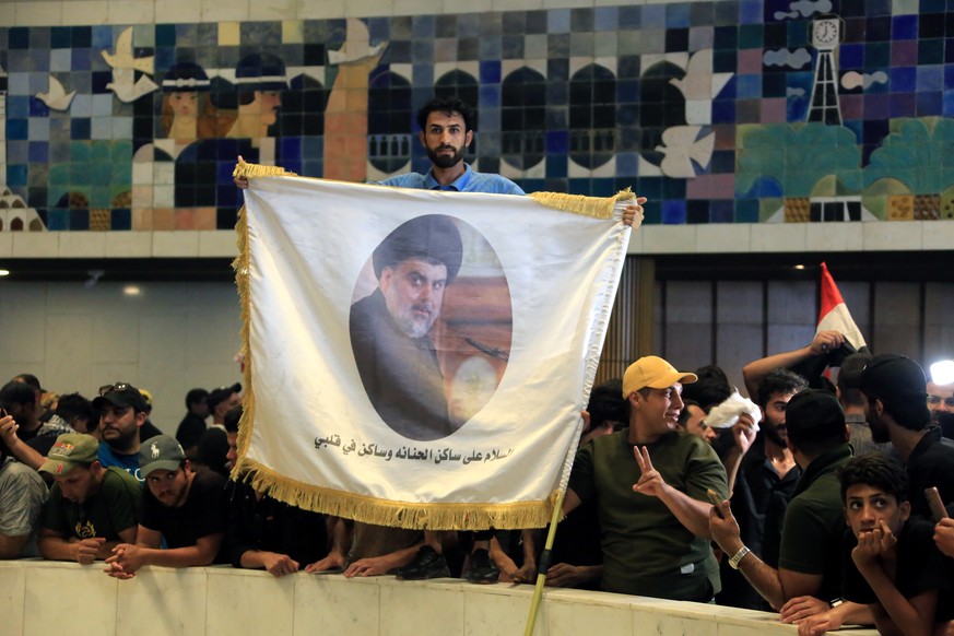 epa10098625 Supporters of Iraqi Shiite cleric Muqtada al-Sadr, head of the Sadrist movement, carry his picture as they gather inside the Iraqi parliament building inside the 'Green Zone' in central Ba ...