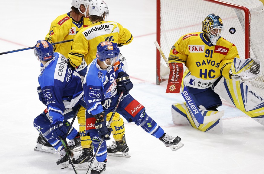 Zuerichs Justin Azevedo, Mitte, und John Quenneville, links, gegen HC Davos&#039; Torhueter Gilles Senn, rechts, und Sven Jung, Mitte hinten, im Eishockey Meisterschaftsspiel der National League zwisc ...