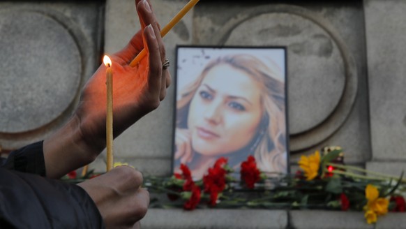A woman holds a candle next to a portrait of slain television reporter Viktoria Marinova during a vigil at the Liberty Monument in Ruse, Bulgaria, Monday, Oct. 8, 2018. Bulgarian police are investigat ...