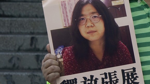 A pro-democracy activist holds placards with the picture of Chinese citizen journalist Zhang Zhan outside the Chinese central government&#039;s liaison office, in Hong Kong, Monday, Dec. 28, 2020. Zha ...