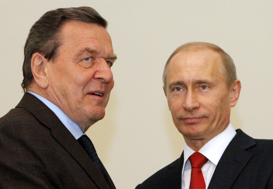 FILE---File photo shows Russian Prime Minister Vladimir Putin, right, and former German chancellor Gerhard Schroeder during their meeting in St. Petersburg, Russia. German Chancellor Olaf Scholz is fl ...