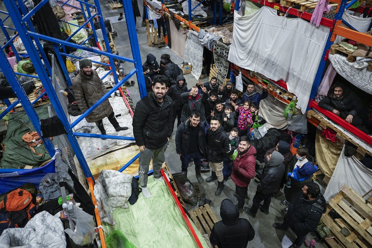 Migrants pose for a photographer at the "Bruzgi" checkpoint logistics center at the Belarus-Poland border near Grodno, Belarus, Tuesday, Dec. 21, 2021. Since Nov. 8, a large group of migrant ...
