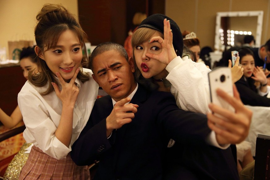 epa05721133 (05/14) Chinese actor Xiao Jiguo (C) poses for a selfie with two actresses in a dressing room while waiting to perform in an entertainment program by Chinese Hunan TV in Beijing city, Chin ...