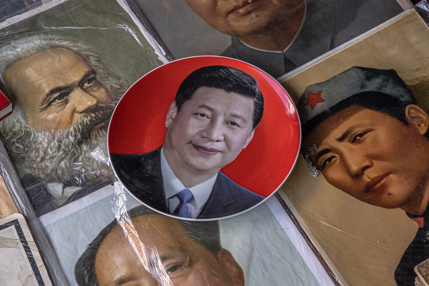 epa09430039 A plate with a picture of Chinese President Xi Jinping lays next to pictures of a former leader Mao Zedong and German philosopher and revolutionary socialist Karl Marx, at the Panjiayuan a ...