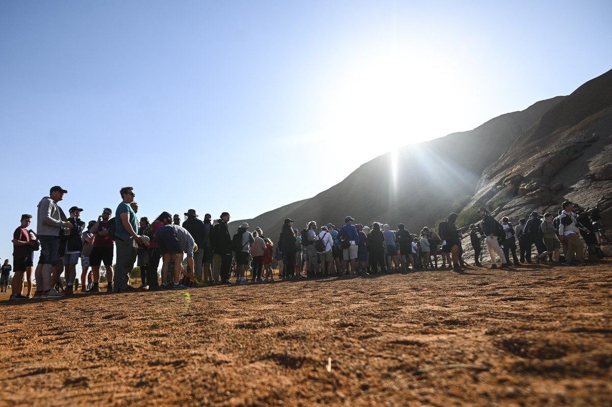 epa07947929 Tourists line up to climb Uluru, also known as Ayers Rock at Uluru-Kata Tjuta National Park in the Northern Territory, Yulara, Australia, 25 October 2019. Climbing Uluru will be banned sta ...