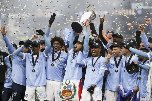New York City FC players celebrate with the trophy after their penalty kick shootout win over the Portland Timbers in the MLS Cup soccer game, Saturday, Dec. 11, 2021, in Portland, Ore. (AP Photo/Aman ...