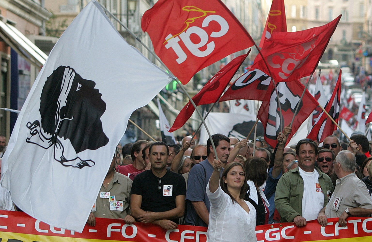 A demonstrator, centre, waves the Corsican flag during the demonstration in Bastia, Corsica Island, Saturday Oct.1, 2005. Youths throwing firecrackers and stones clashed with police Saturday after hun ...