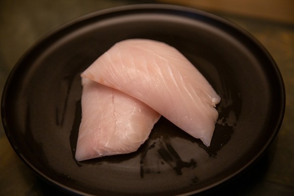 Red Snapper ... or not? Fish filets on black plate.