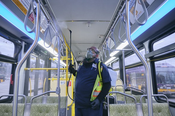 epa08273475 King County Metro equipment service worker Raymond Determann sprays the interior of a King County Metro Transit bus with disinfectant cleaner in response to the Seattle-area novel coronavi ...
