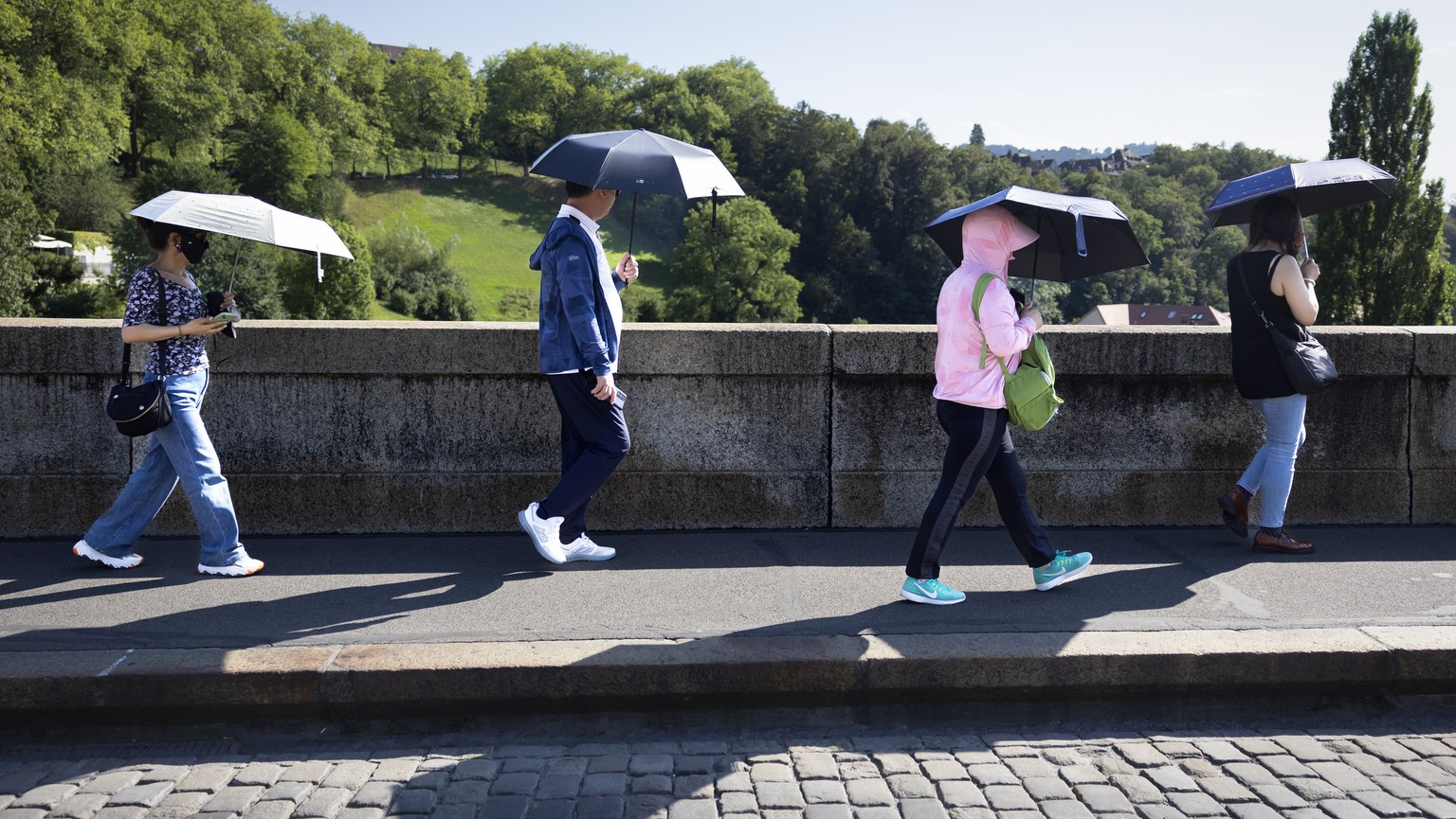 Touristen aus China schuetzen sich mit einem Schirm gegen die Sonne, am Dienstag, 22. August, 2023 in Bern. (KEYSTONE/Peter Klaunzer)